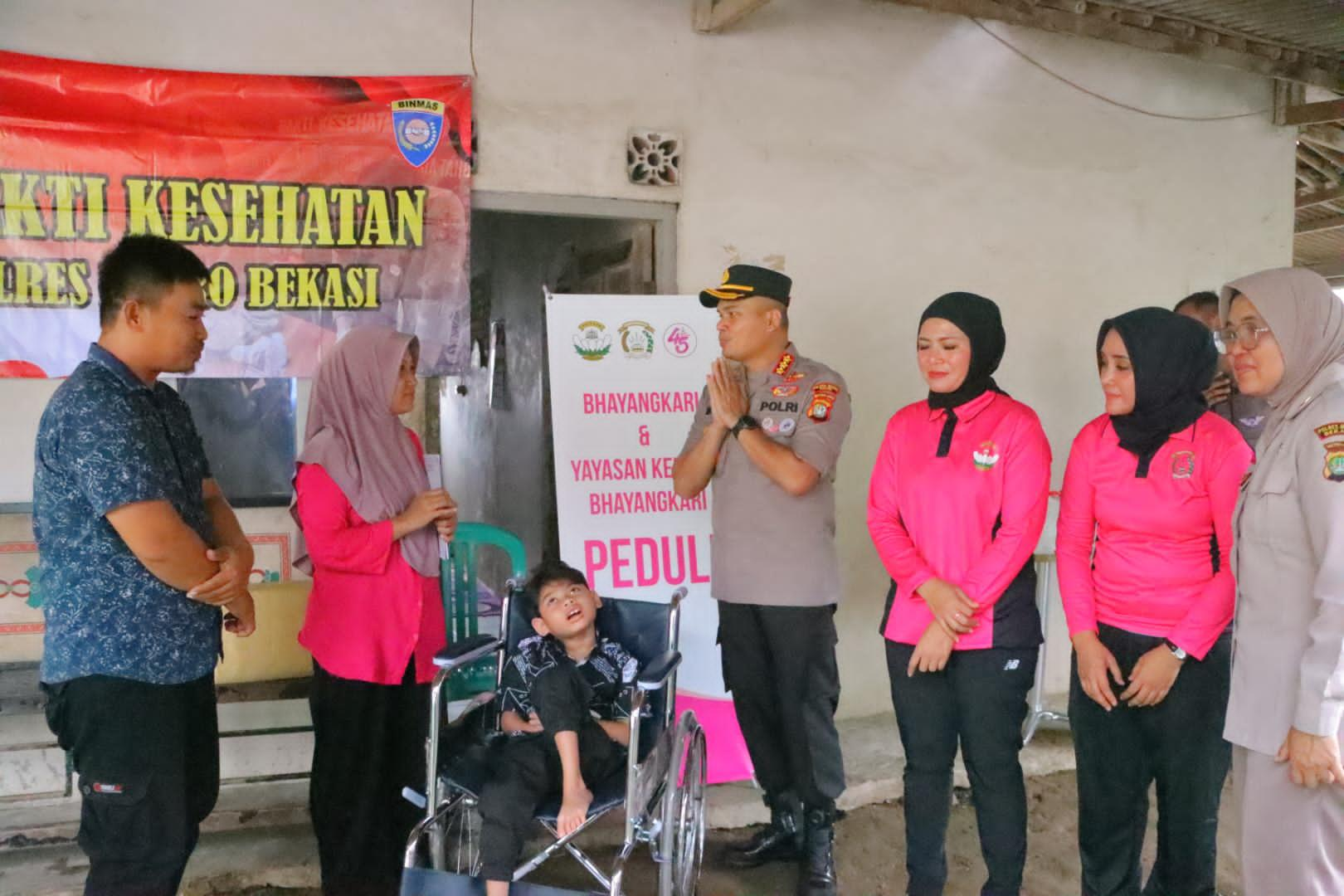 Kapolres Metro Bekasi Bersama Ketua Bhayangkari Cabang Metro Bekasi Berikan Kursi Roda untuk Warga Disabilitas di Cikarang Utara